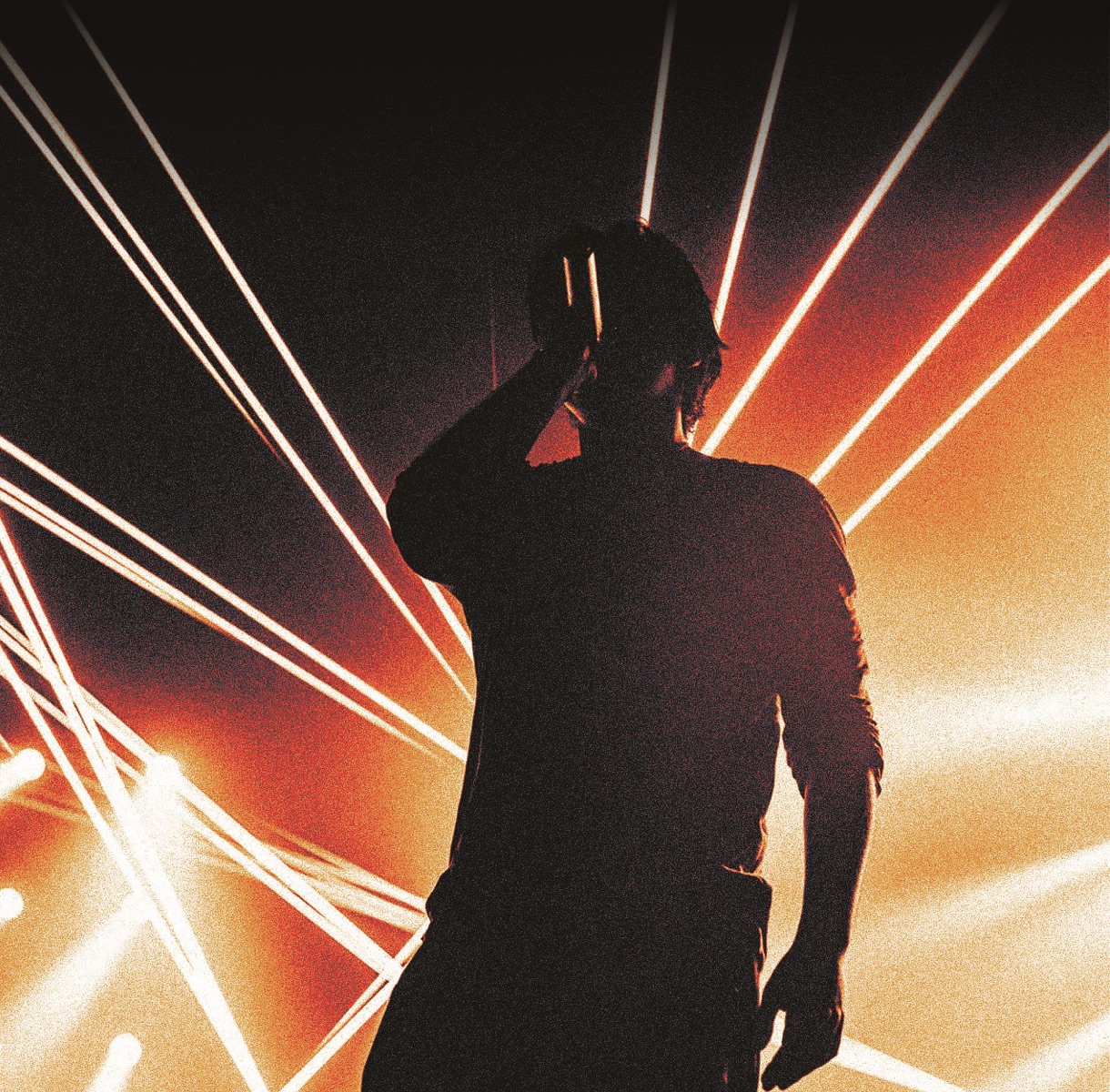 Ian Asher silhouetted against a fan of white and amber lasers